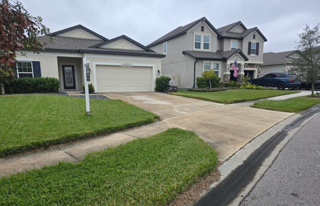Driveway pressure washing in progress, clean and dirty sections side by side