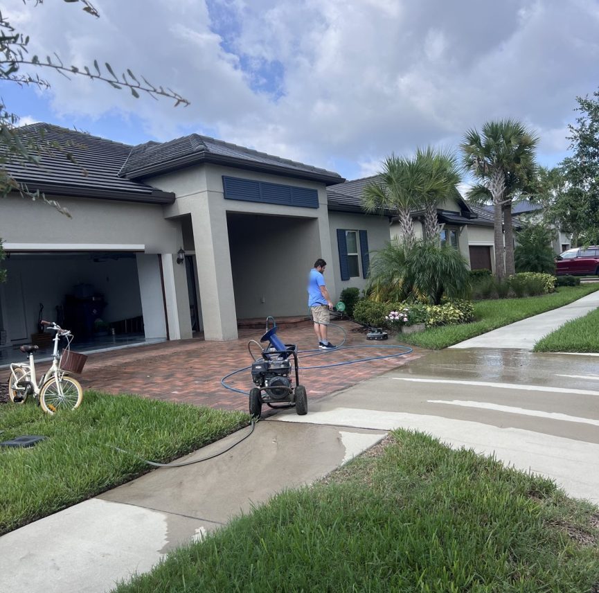 Aqua Blast crew cleaning a paver driveway and sidewalk at a home